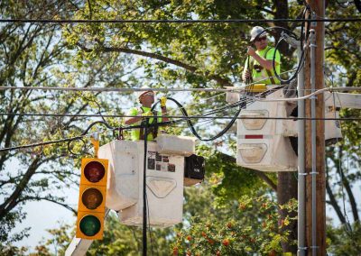 Electrical workers in bucket trucks install traffic signals